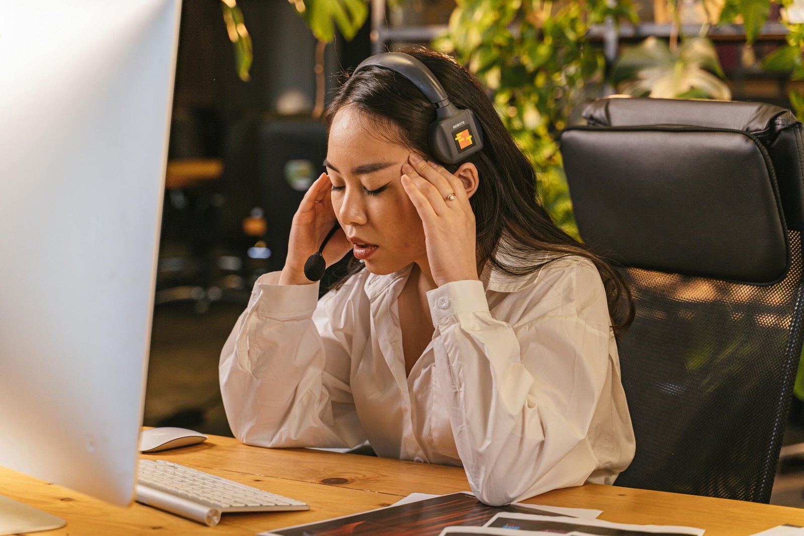 Young woman in headset with fingers to temples