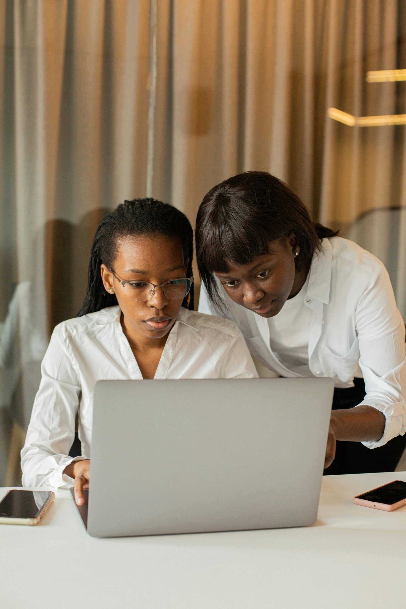 young, black support worker, over shoulder of client with laptop